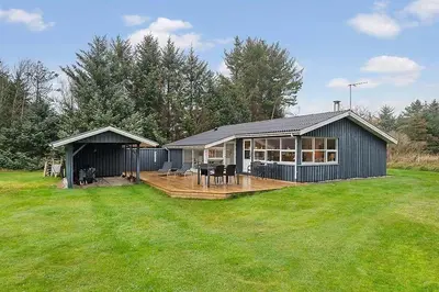 a large house with a deck in a yard at BL1451-Blokhus-Quintusvej-5 in Blokhus