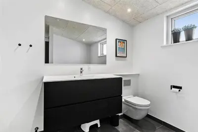 a bathroom with a sink and a toilet and a mirror at BL1110-Blokhus-Bloksbjerg-7 in Blokhus