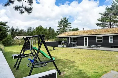 a swing in a yard in front of a house at BL1110-Blokhus-Bloksbjerg-7 in Blokhus
