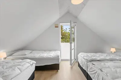 a attic room with two beds and a window at BL1506-Saltum-Kronhjortvej-15 in Saltum