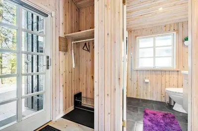 a wooden bathroom with a toilet and a window at BL387-Blokhus-Berberisvej-51 in Blokhus