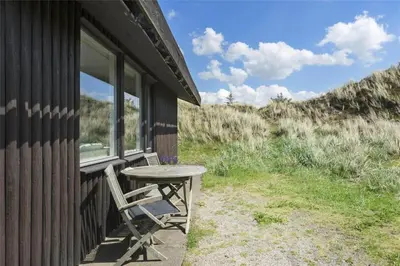 a table and a chair on the porch of a cabin at BL808-Pandrup-Hare-hop-5 in Pandrup