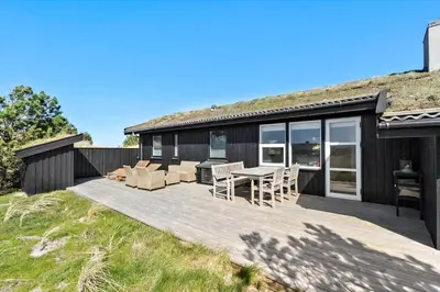 a house with a wooden deck with a table and chairs at BL1408-Pandrup-Hunetorp-Klitvej-243 in Pandrup