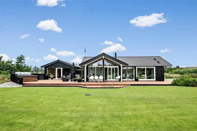 a house with a large deck with a green yard at BL425-Saltum-Tippen-22 in Saltum