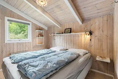 a bedroom with a large bed in a wooden wall at BL1052-Blokhus-Berberisvej-22 in Blokhus