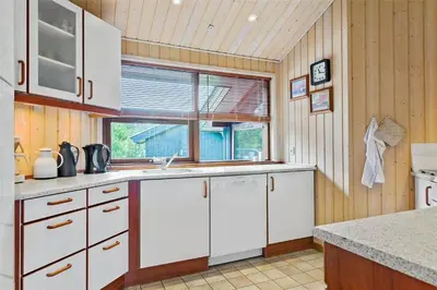 a kitchen with white cabinets and a window at BL160-Blokhus-Bag-Hojen-68 in Blokhus