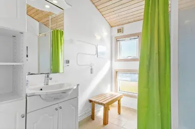 a bathroom with a sink and a green shower curtain at BL826-Saltum-Haresvinget-7 in Saltum