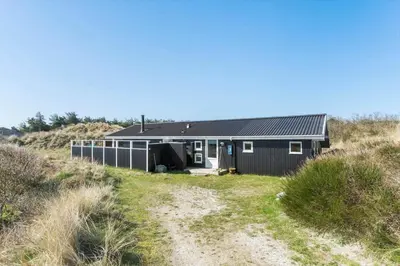 a black house sitting on top of a beach at BL826-Saltum-Haresvinget-7 in Saltum
