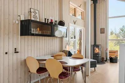a dining room with a table and chairs and a fireplace at BL1702-Blokhus-Krylevej-3 in Blokhus