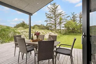 a wooden deck with a table and chairs on it at BL1411-Blokhus-Ribergaardsvej-15 in Blokhus