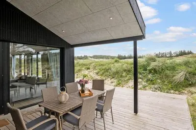 a patio with a table and chairs on a deck at BL1411-Blokhus-Ribergaardsvej-15 in Blokhus