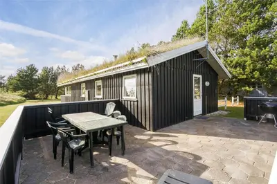 a black house with a table and chairs on a patio at BL1066-Pandrup-Rodhus-Skolevej-17 in Pandrup