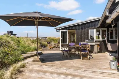 a patio with a table and an umbrella at BL137-Blokhus-Pirupshvarre-Klit-6 in Blokhus