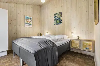 a bedroom with a bed in a room with wooden walls at BL1379-Blokhus-Saetergaardsvej-8 in Blokhus
