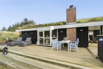 a wooden deck with chairs and a table on a house at BL1379-Blokhus-Saetergaardsvej-8 in Blokhus