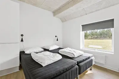 two beds in a white room with a window at BL1169-Blokhus-Berberisvej-5 in Blokhus
