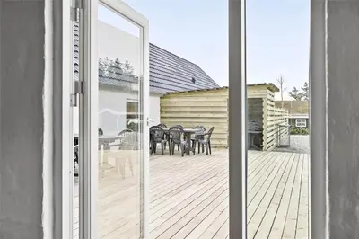 a sliding glass door of a patio with a table and chairs at BL1169-Blokhus-Berberisvej-5 in Blokhus