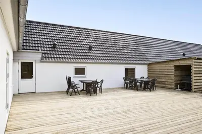 a patio with tables and chairs and a building at BL1169-Blokhus-Berberisvej-5 in Blokhus