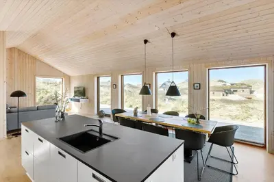 a kitchen with a sink and a table with chairs at BL1350-Blokhus-Taarnfalkevej-29 in Blokhus