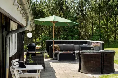 a patio with a couch and an umbrella at BL1336-Blokhus-Berberisvej-18 in Blokhus