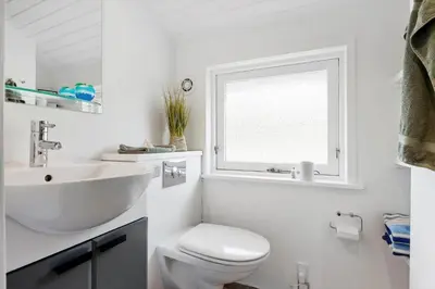 a bathroom with a sink and a toilet and a window at BL1336-Blokhus-Berberisvej-18 in Blokhus