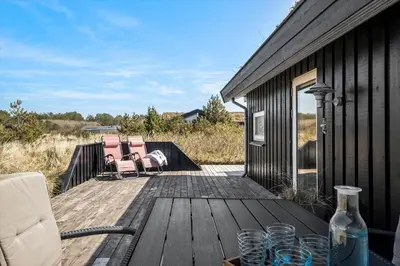a wooden deck with two chairs and a table on it at BL112-Saltum-Kvansletten-20 in Saltum