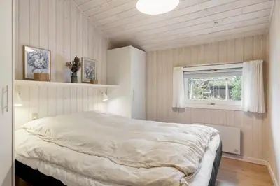 a bedroom with a white bed in a room with a window at BL1254-Pandrup-Rodhusparken-25 in Pandrup