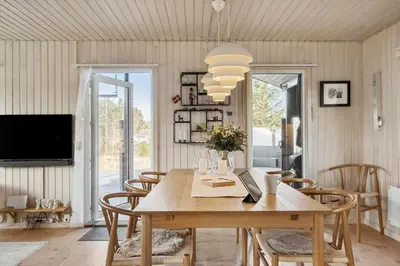 a dining room with a table and chairs and a television at BL1502-Blokhus-Graevlingevej-3 in Blokhus