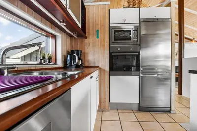 a kitchen with stainless steel appliances and a window at BL1203-Blokhus-Pirupshvarrevej-23 in Blokhus