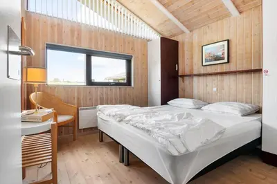a bedroom with a bed and a desk and a window at BL1203-Blokhus-Pirupshvarrevej-23 in Blokhus