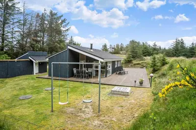 a small house with a playground in the yard at BL180-Blokhus-Soren-Petersvej-22 in Blokhus