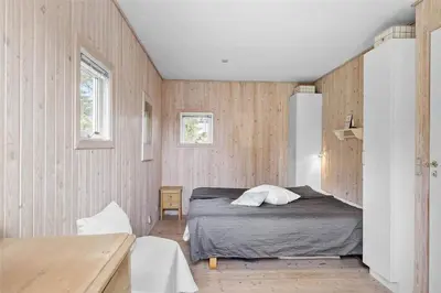 a bedroom with a bed and wooden walls at BL1556-Blokhus-Poppelvej-1 in Blokhus