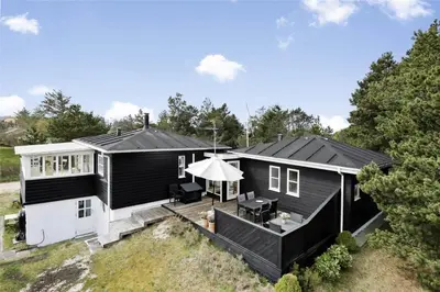 a black and white house with a patio at BL1556-Blokhus-Poppelvej-1 in Blokhus