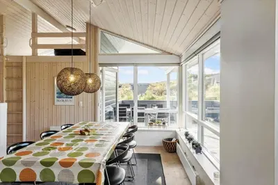a dining room with a long table and some windows at BL325-Blokhus-Lyngvej-11 in Blokhus
