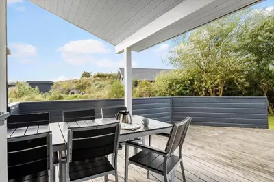 a patio with a table and chairs on a deck at BL325-Blokhus-Lyngvej-11 in Blokhus