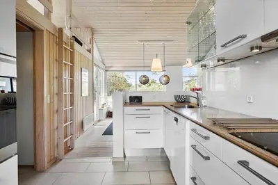 a kitchen with white cabinets and a large window at BL325-Blokhus-Lyngvej-11 in Blokhus