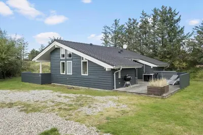 a tiny house with a deck in a yard at BL325-Blokhus-Lyngvej-11 in Blokhus