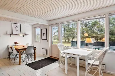 a dining room with a table and chairs and windows at BL488-Pandrup-Akelejevej-10 in Pandrup