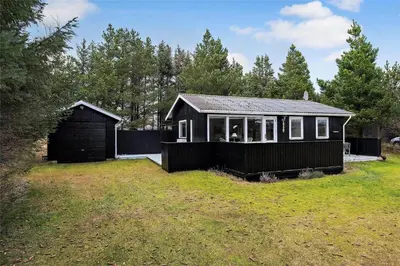 a small black house in a grassy yard at BL488-Pandrup-Akelejevej-10 in Pandrup