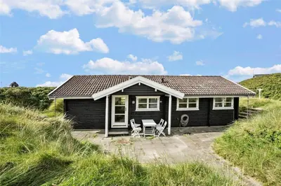 a small black house with two chairs in front of it at BL1665-Saltum-Borgvej-57 in Saltum