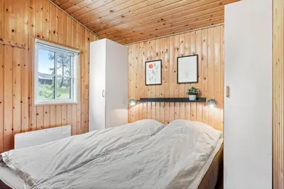 a bedroom with a bed in a wooden wall at BL1437-Blokhus-Berberisvej-78 in Blokhus
