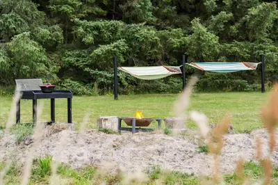 two hammocks and a table and a fire in a field at BL127-Saltum-Laustvej-22 in Saltum