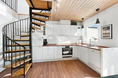 a kitchen with white cabinets and a spiral staircase at BL1251-Blokhus-Vigen-9-B in Blokhus