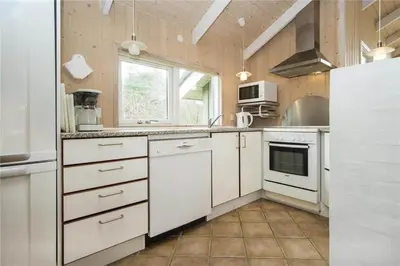 a large kitchen with white cabinets and a window at BL481-Pandrup-Rodhusparken-10 in Pandrup