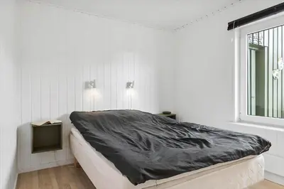 a white room with a bed and a window at BL1216-Blokhus-Gyvelvej-13 in Blokhus