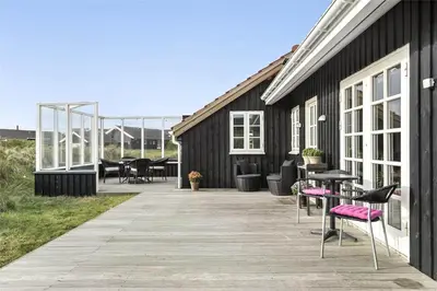 a deck with chairs and tables on a house at BL964-Blokhus-Klitvejen-28 in Blokhus