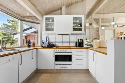 a kitchen with white cabinets and a large window at BL1600-Saltum-Daadyrvej-25-A in Saltum