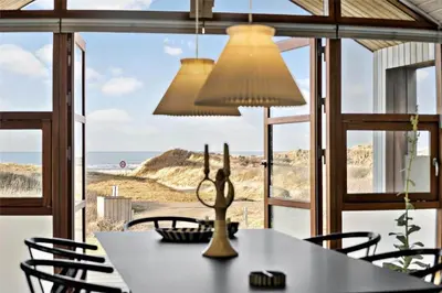 a dining room with a table and a view of the beach at BL1733-Blokhus-Dahl-Iversensvej-5 in Blokhus
