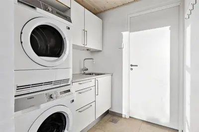 a white laundry room with a washer and dryer at BL1733-Blokhus-Dahl-Iversensvej-5 in Blokhus