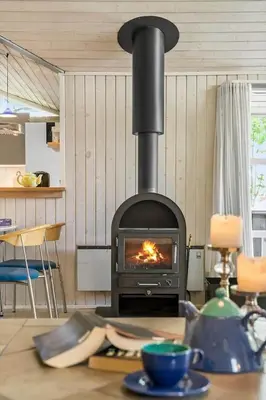 a stove in a living room with a table with a table sidx sidx at BL226-Blokhus-Paa-Bakken-13 in Blokhus